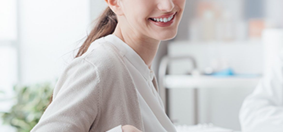 Uśmiechnięta kobieta siedząca przy biurku