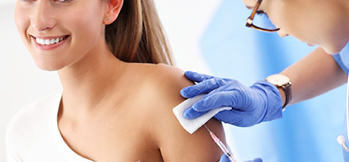 Lekarka wykonuje uśmiechniętej kobiecie szczepienie w ramię