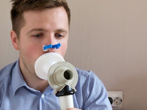 Mężczyzna wykonujący badanie spirometrem